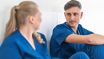 Male and female nurses sit and talk.