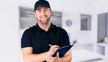 Man in dark blue polo with dark blue cap holding pen and board